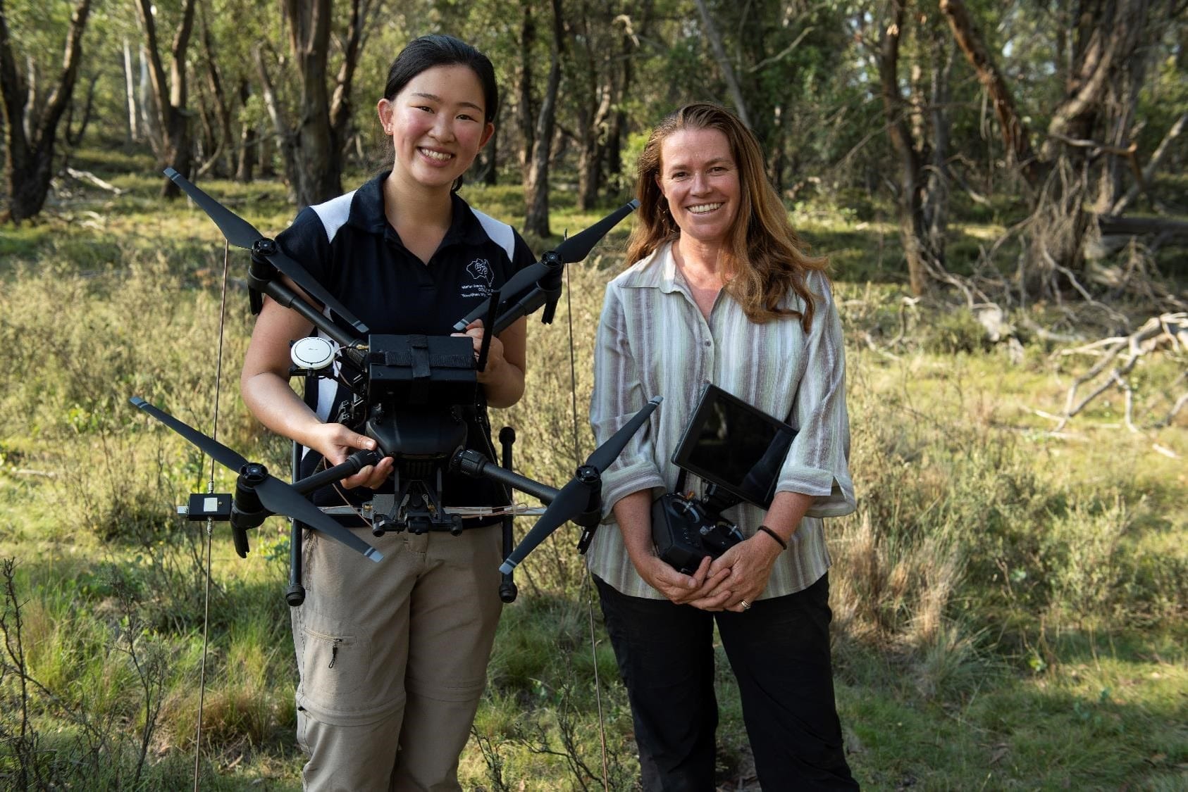 laura is holding a drone and debbie is holding the drone controller as they smile at the camera rosenbergs goannas project