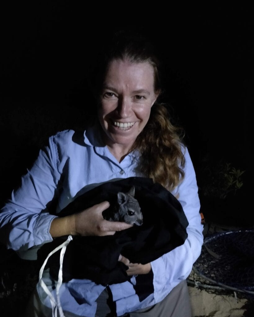 Debbie holding a hare wallaby that is sitting in a black bag waiting to be released