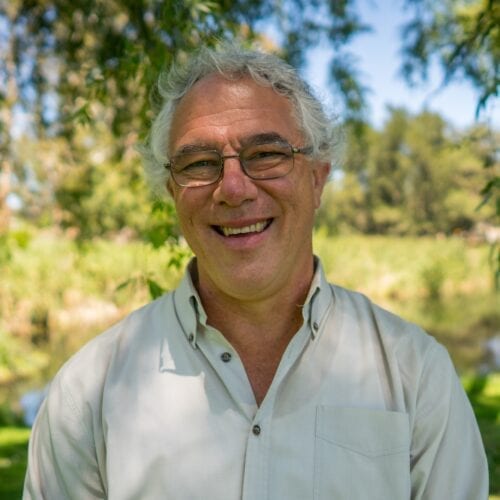 a smiling man with glasses and grey hair